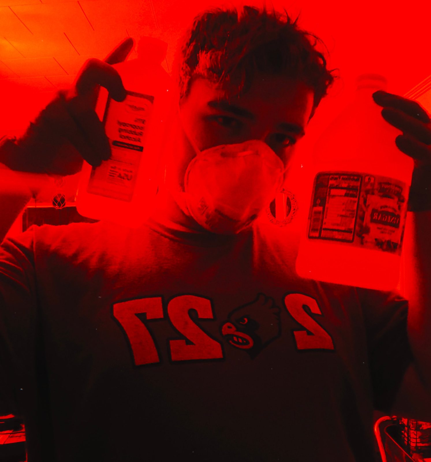 Nathan Etes holding two bottles, lit in deep red