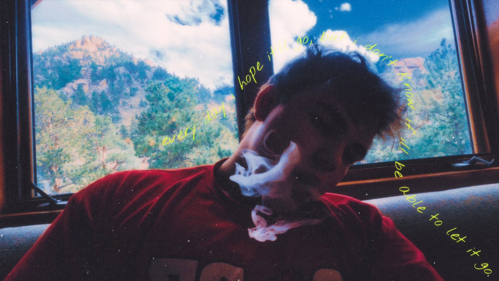 Nathan Etes by a window with mountains outside, smoke around his face