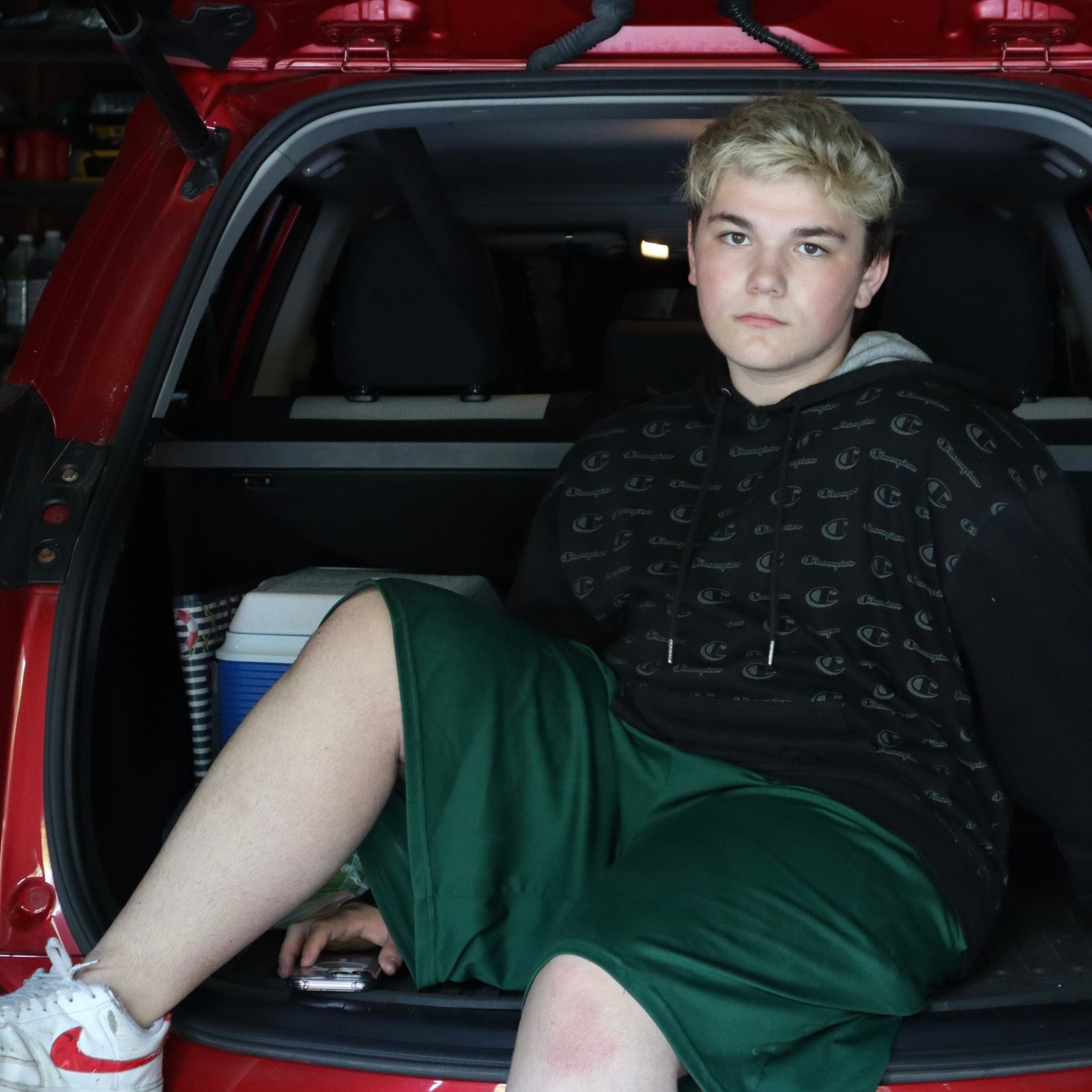 Nathan Etes sitting in the open back of a red car