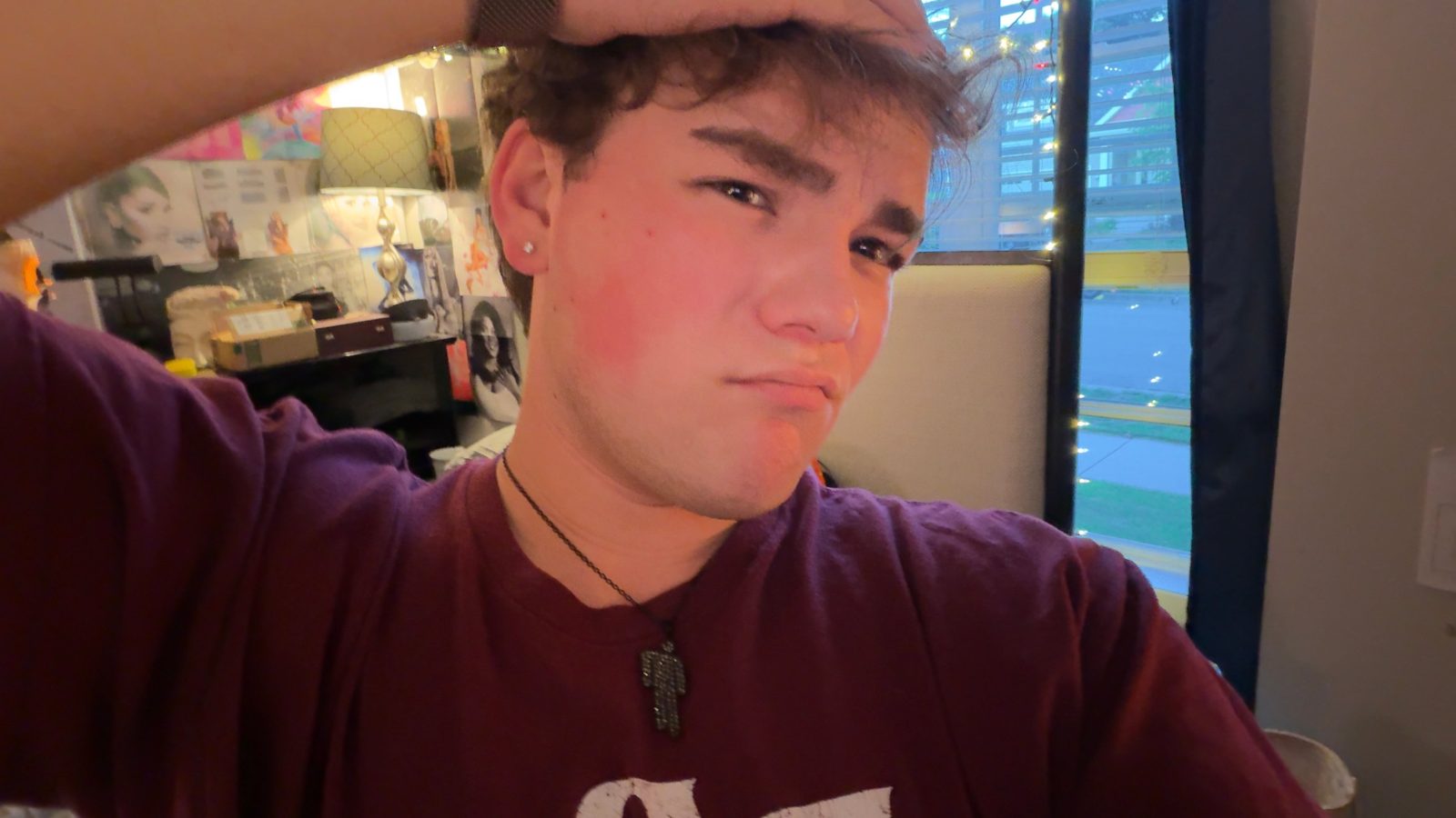 Nathan Etes in a maroon shirt with string lights behind him